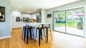 A modern kitchen with white cabinets, a central island, and bar stools. - 3-bedroom house in pleasant Paso Robles with cool vibes (Paso Robles)