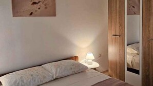 A bedroom with a bed, a nightstand, a lamp, and a wardrobe. - Holiday apartment mit Klimaanlage (Pula)