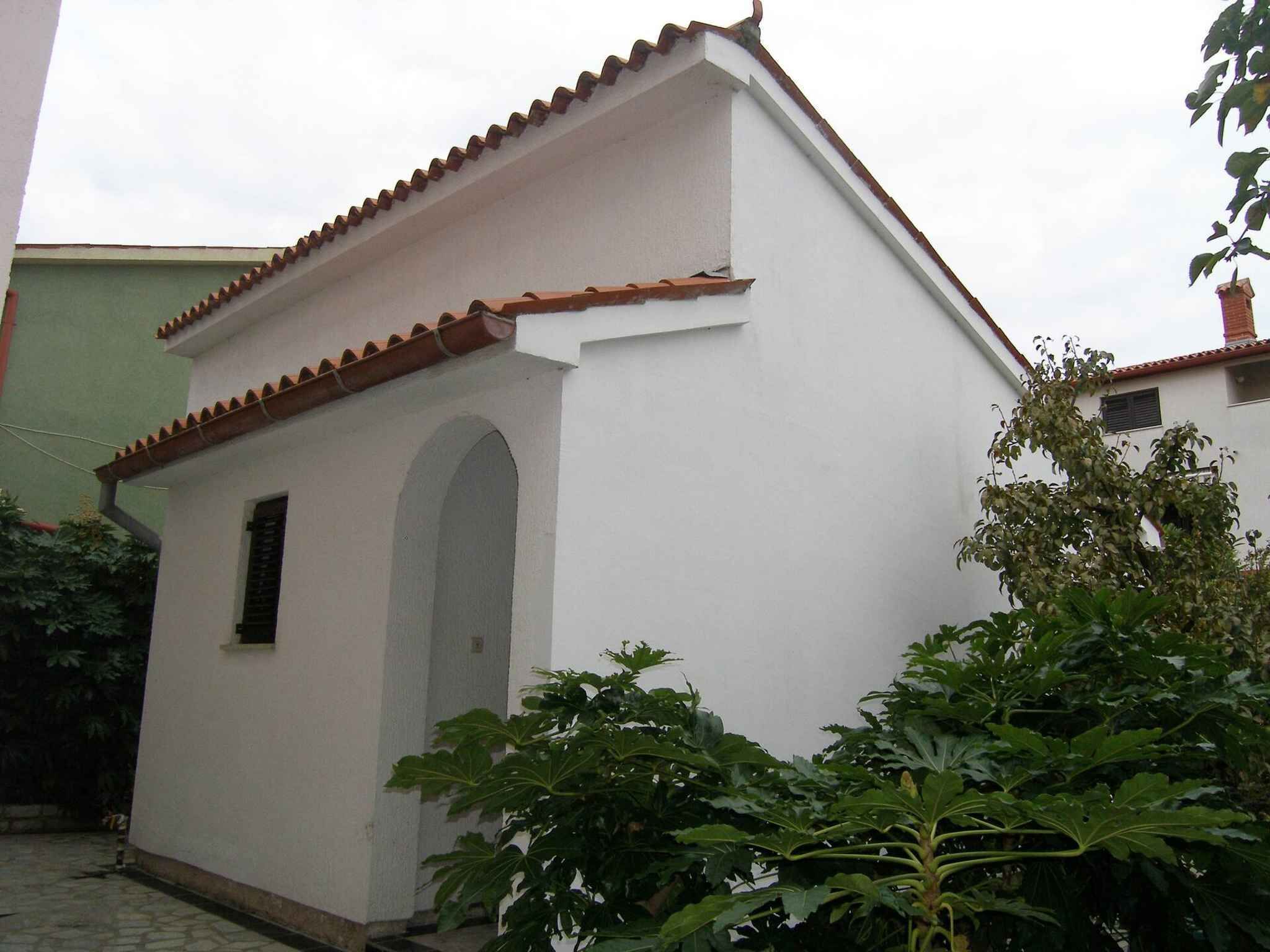 A small, white building with a tiled roof and an arched entrance.