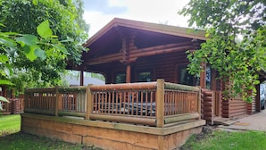 A log cabin with a wooden deck and a covered porch. - Bumblebee Log Cabin Felmoor Park (Northumberland)