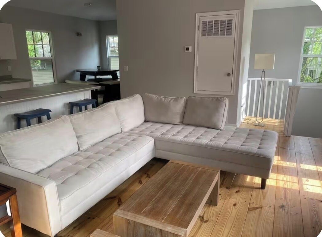 A modern living room with a sectional sofa, a wooden coffee table, and a dining area with a table and chairs.