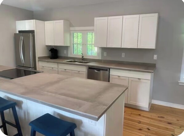 A modern kitchen with white cabinets, stainless steel appliances, and a central island with bar stools.