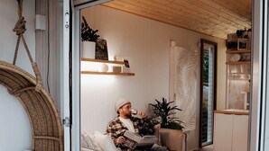 A cozy room with a bed, a hanging chair, and a small table with a plant.