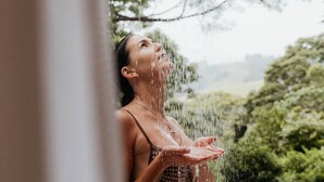 A person in a bikini under a shower with water falling.