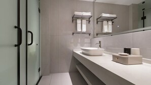 A modern bathroom with a glass shower enclosure, a large mirror, and a white sink with a modern faucet. - Yixinju Holiday Homestay (Zhangjiajie)