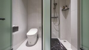 A modern bathroom with a toilet, a shower, and a shelf with toiletries. - Yixinju Holiday Homestay (Zhangjiajie)