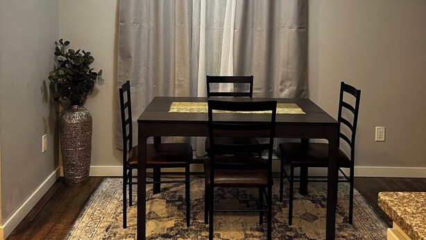 A dining area with a table, chairs, a vase with plants, and a patterned rug. - Terrific 3-bedroom townhome with AC in charming Fargo, Central location (Fargo)