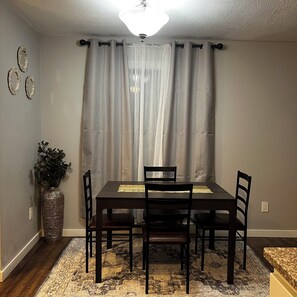 A dining area with a table, chairs, a vase with plants, and a patterned rug. - Terrific 3-bedroom townhome with AC in charming Fargo, Central location (Fargo)