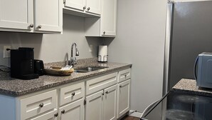 A kitchen with white cabinets, a stainless steel sink, a coffee maker, and a refrigerator. - Terrific 3-bedroom townhome with AC in charming Fargo, Central location (Fargo)