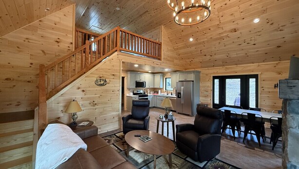 Ein Holzblock-Innenraum mit Treppe, Wohnzimmer, Essbereich und Küche sowie großen Fenstern.