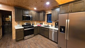 Una cucina moderna con elettrodomestici in acciaio inossidabile, soffitto in legno e forno a microonde integrato.