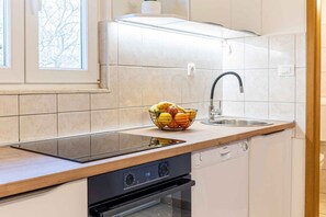 Une cuisine moderne équipée d’un four encastré, d’un lave-vaisselle, d’un évier et d’un panier à fruits posé sur le plan de travail.