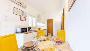 Una cucina compatta con forno a microonde, lavandino e sedie gialle.