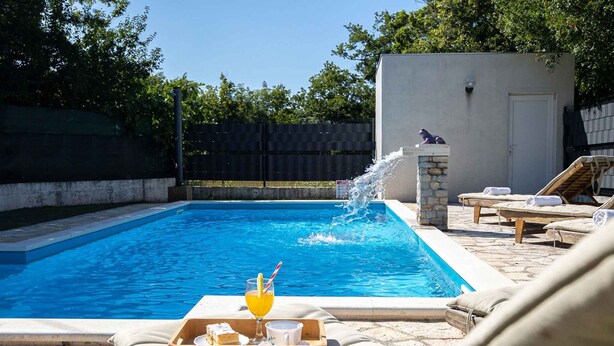 Una piscina con lettini e un vassoio con bevande e snack.