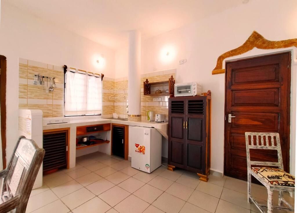 A compact kitchen with a refrigerator, microwave, and wooden cabinets.