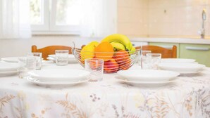 A dining table set with plates, glasses, and a fruit bowl. - Holiday apartment with air conditioning and terrace (Medulin)