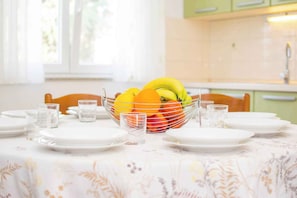 A dining table set with plates, glasses, and a fruit bowl. - Holiday apartment with air conditioning and terrace (Medulin)