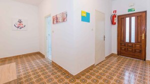 A hallway with patterned floor tiles, a wooden door with a green exit sign, and a fire extinguisher mounted on the wall. - Holiday apartment mit Klimaanlage (Medulin)