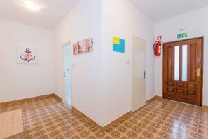 A hallway with patterned floor tiles, a wooden door with a green exit sign, and a fire extinguisher mounted on the wall. - Holiday apartment mit Klimaanlage (Medulin)