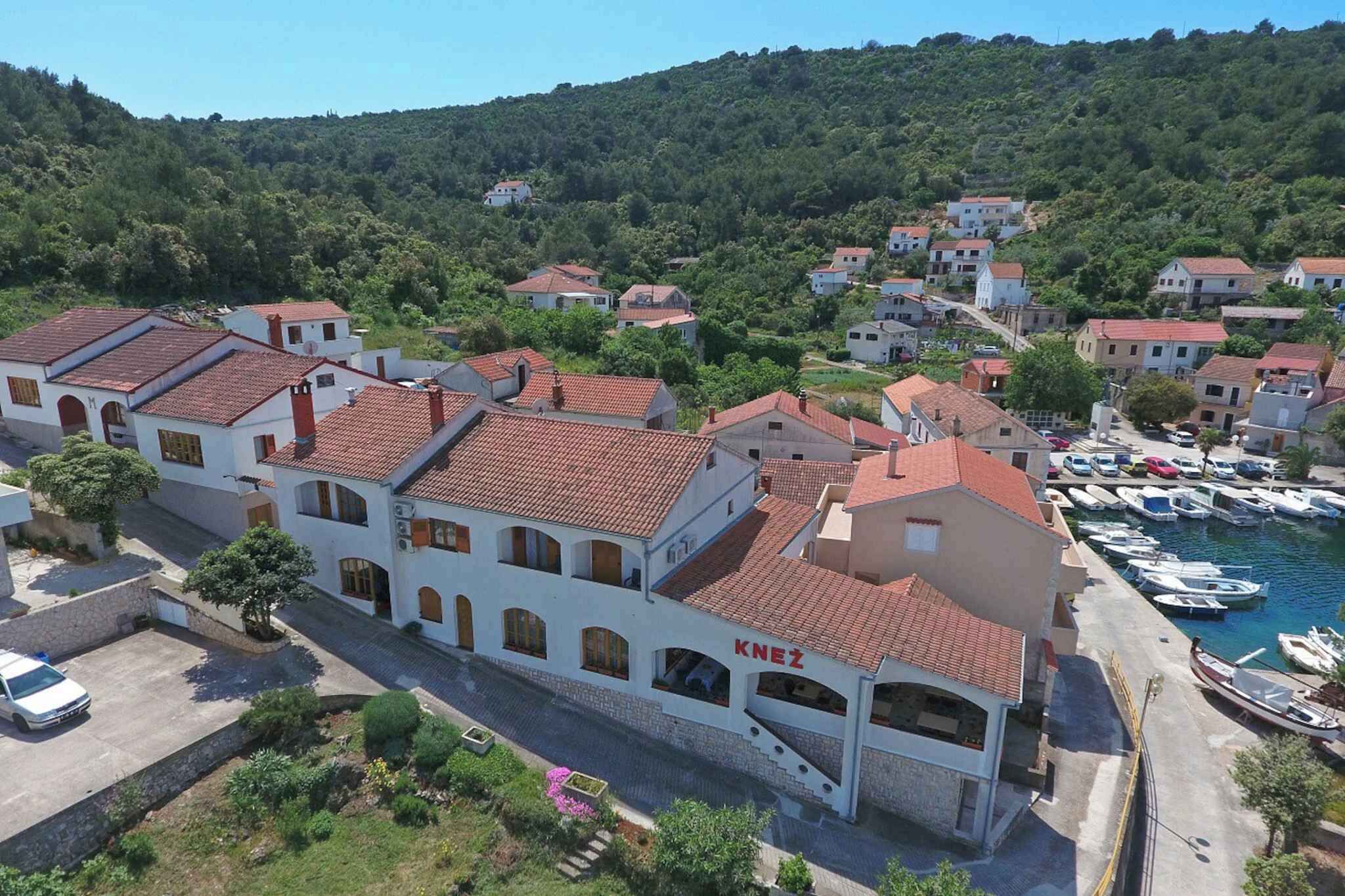 Une ville côtière aux bâtiments blancs, dotée d’un port de plaisance et bordée de collines.