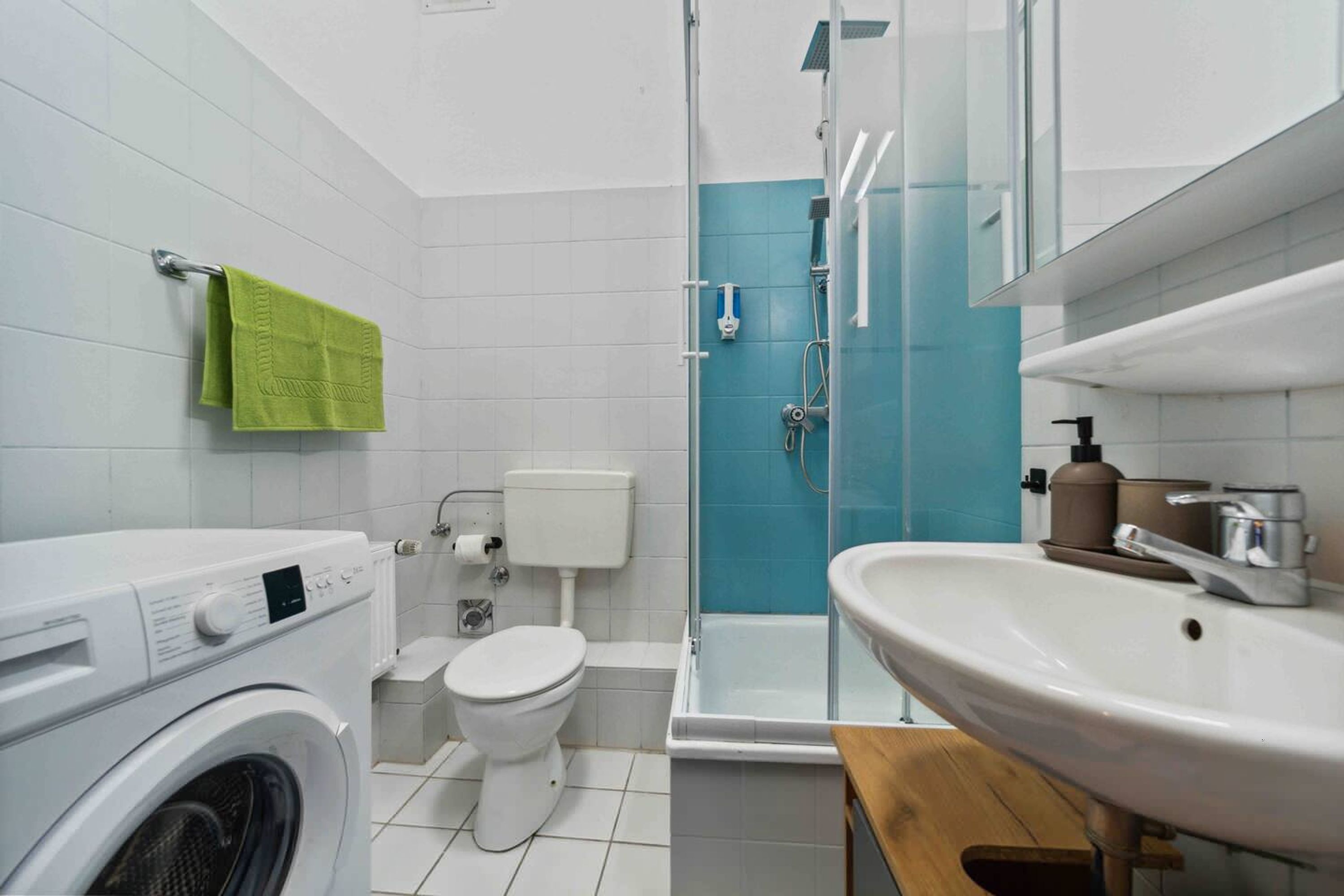 Un baño moderno con lavadora, inodoro, ducha y lavamanos.