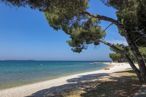 A beach with clear blue water, a sandy shore, and a few people relaxing. - Holiday apartment mit Klimaanlage und Terrasse (Valbandon)