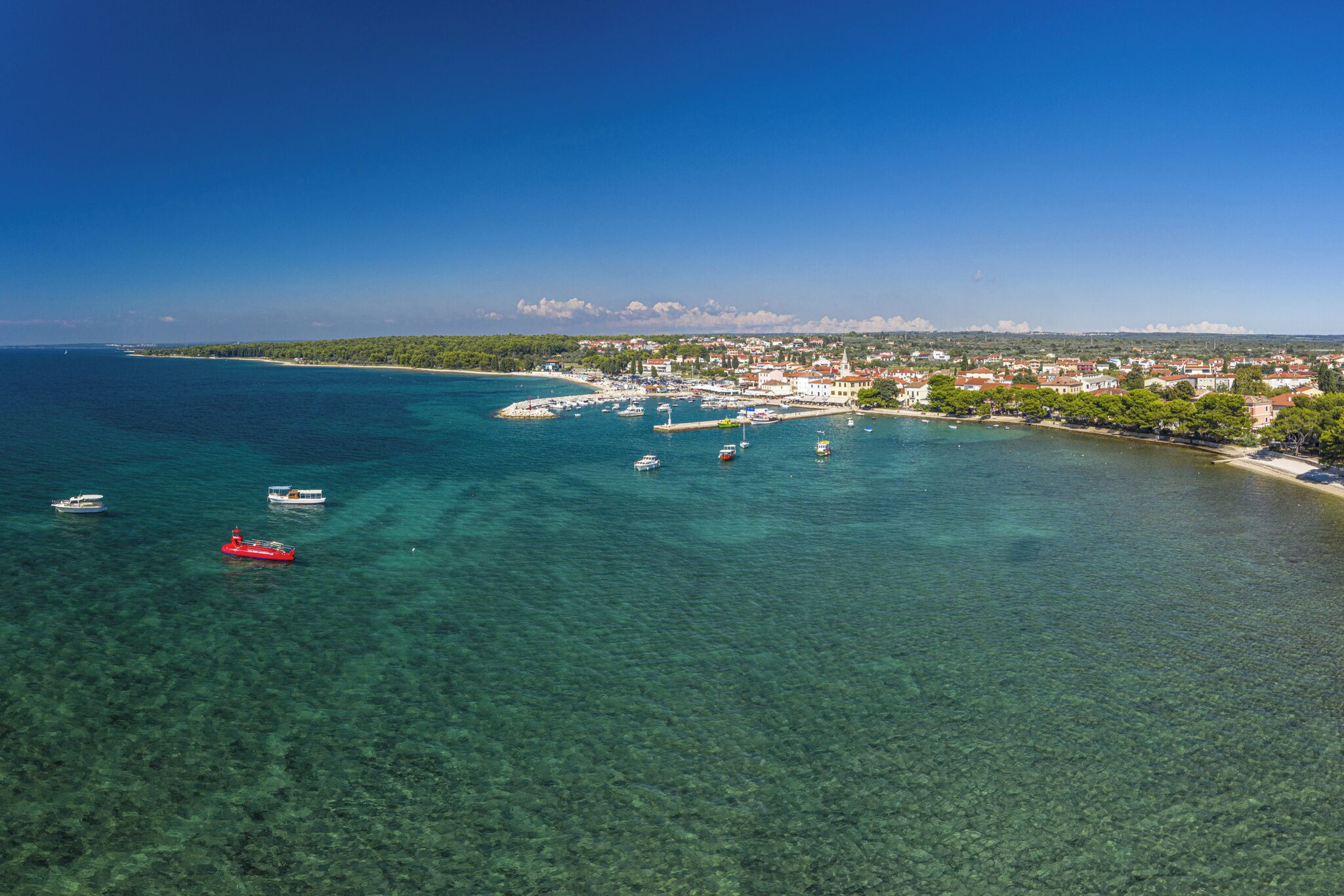 A coastal town with clear waters, boats, and buildings along the shore.