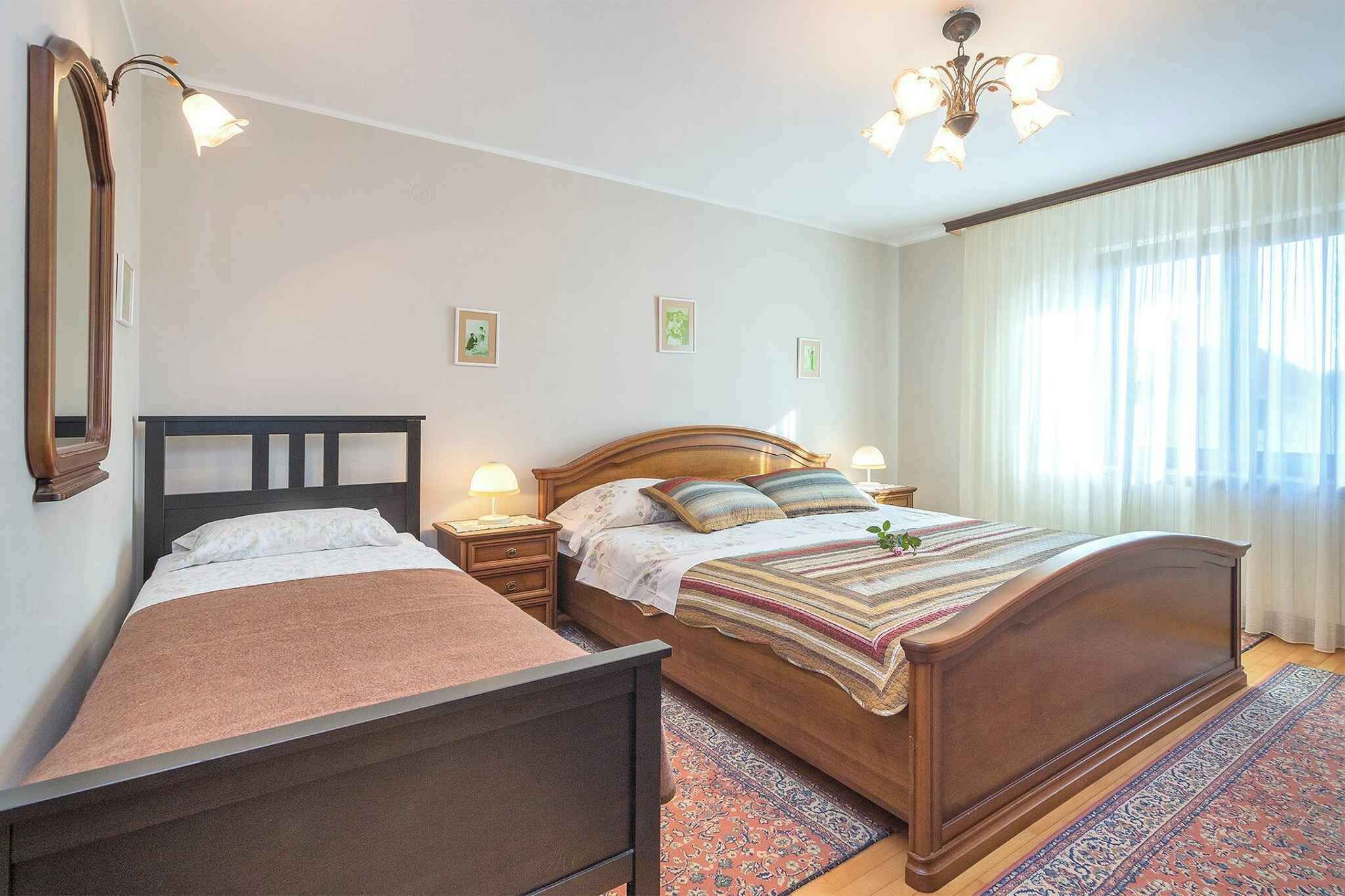 A bedroom with two beds, a nightstand, a mirror, and a chandelier.