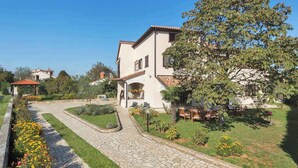 A two-story house with a paved driveway leading to a patio area. - Holiday apartment mit Klimaanlage (Valbandon)