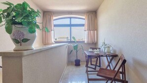 A balcony with a table, chairs, a potted plant, and a window with curtains. - Holiday apartment mit Klimaanlage (Valbandon)
