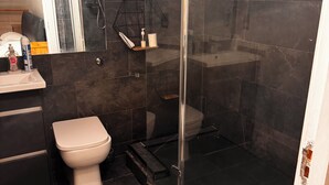 Un baño moderno con ducha de vidrio, inodoro y tocador con espejo.