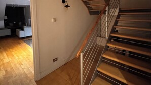Una escalera con escalones de madera y barandillas de metal, que conduce a un piso superior.
