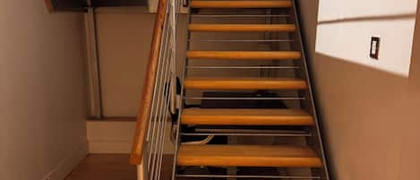 Eine Holztreppe mit Metallgeländern, die zu einer oberen Etage führt.
