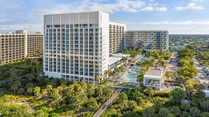 Ein moderner Hotelkomplex mit mehreren Hochhäusern, einem zentral gelegenen Schwimmbecken und üppiger Bepflanzung.