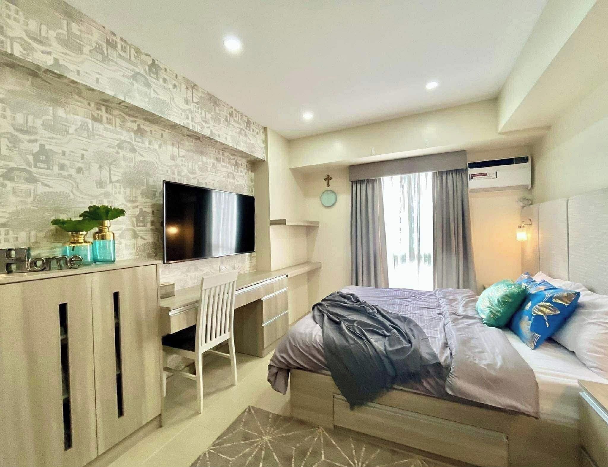 Un dormitorio moderno con cama, escritorio y televisor.