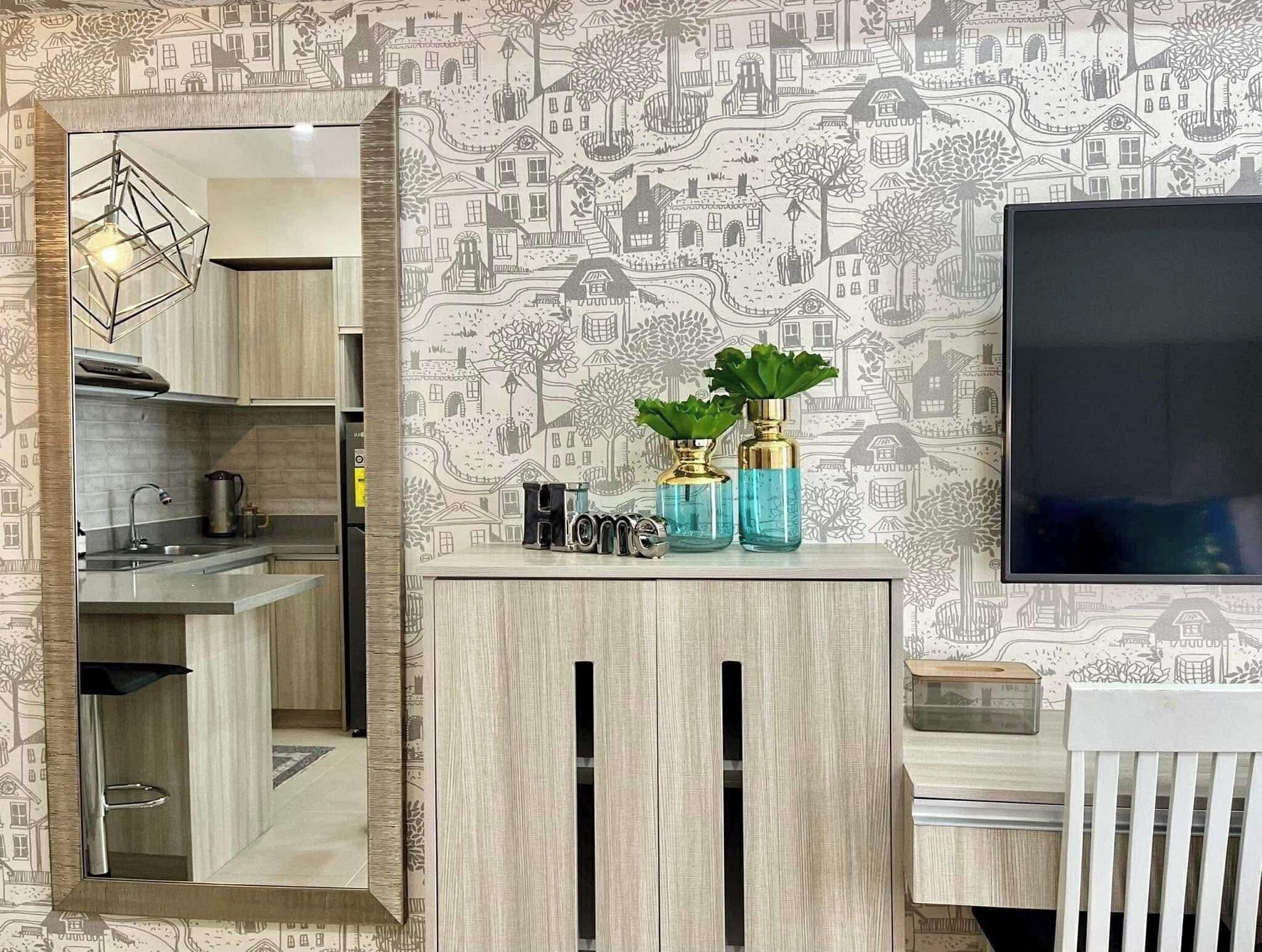 A modern kitchen with a built-in stove, a sink, and a mirrored cabinet. There are two decorative vases on the counter.