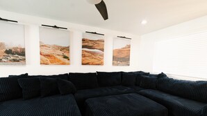 A modern living room with a sectional sofa, wall-mounted artwork, and a ceiling fan. - Private Pool Oasis • 10 Min to Westgate & State Farm Stadium (Phoenix)