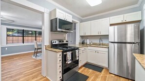 Una cocina moderna con armarios blancos, electrodomésticos de acero inoxidable y suelo de madera.