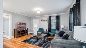 Una sala de estar moderna con un sofá, dos sillones, una mesa de centro y un televisor.