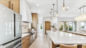 Una cocina moderna con una isla grande, electrodomésticos de acero inoxidable e iluminación colgante.