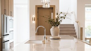 Una cocina moderna con encimera de mármol, electrodomésticos de acero inoxidable y un florero con ramas.