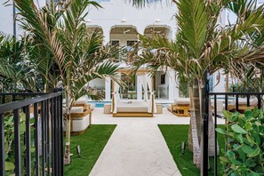 Un espace aménagé au bord de la piscine, avec un chemin menant à un coin salon abrité par un auvent.
