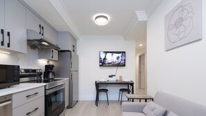 A modern kitchen with a built-in oven, microwave, and coffee maker, a dining area with a table and chairs, and a sofa. - New Vancouver Kerrisdale Suite mins to Yvr/Ubc (Vancouver)