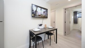 A modern dining area with a flat-screen TV mounted on the wall, a wooden table with two chairs, and a door leading to another room. - New Vancouver Kerrisdale Suite mins to Yvr/Ubc (Vancouver)