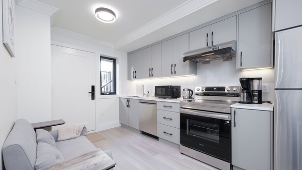 A modern kitchen with grey cabinets, a built-in oven, a microwave, and a refrigerator. - New Vancouver Kerrisdale Suite mins to Yvr/Ubc (Vancouver)