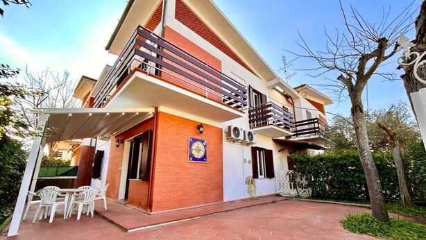 A two-story house with a balcony, a patio with chairs, and a clock on the wall. - Casa Marina [30 mt from the sea, wifi, park, seaview] (Marcelli)
