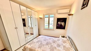 A bedroom with a bed, a wardrobe, a window, and an air conditioning unit. - Casa Marina [30 mt from the sea, wifi, park, seaview] (Marcelli)