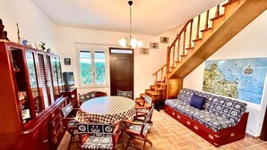 A cozy living room with a dining table, chairs, a sofa, a staircase, and a large map on the wall. - Casa Marina [30 mt from the sea, wifi, park, seaview] (Marcelli)