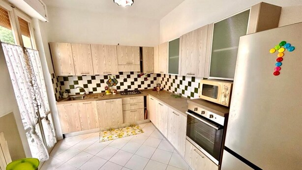 A kitchen with wooden cabinets, a microwave, a stove, and a refrigerator. - Large quadrilo with p.auto and a/c near the sea (Marcelli)