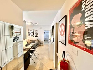 A modern kitchen with a dining area, white cabinets, and a fire extinguisher mounted on the wall. - Gianluca apt [center, close to the beach, modern] (Numana)